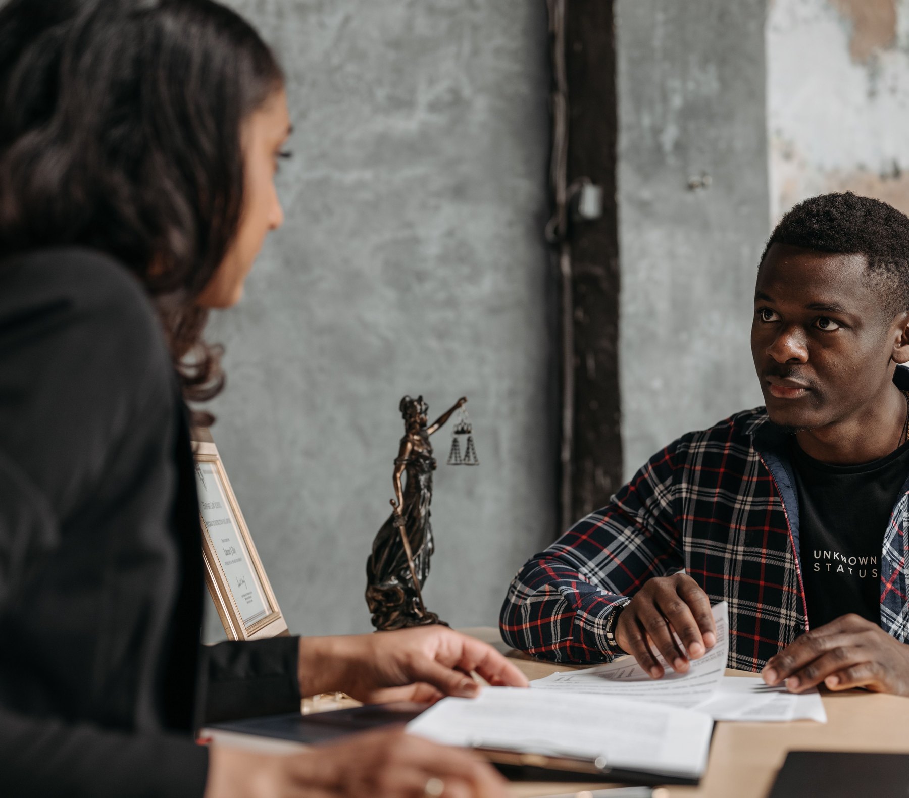 An immigration professional and a client talking across a desk, documents open between them.